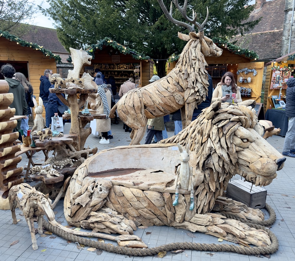 a wooden sculpture of a deer laying on the ground