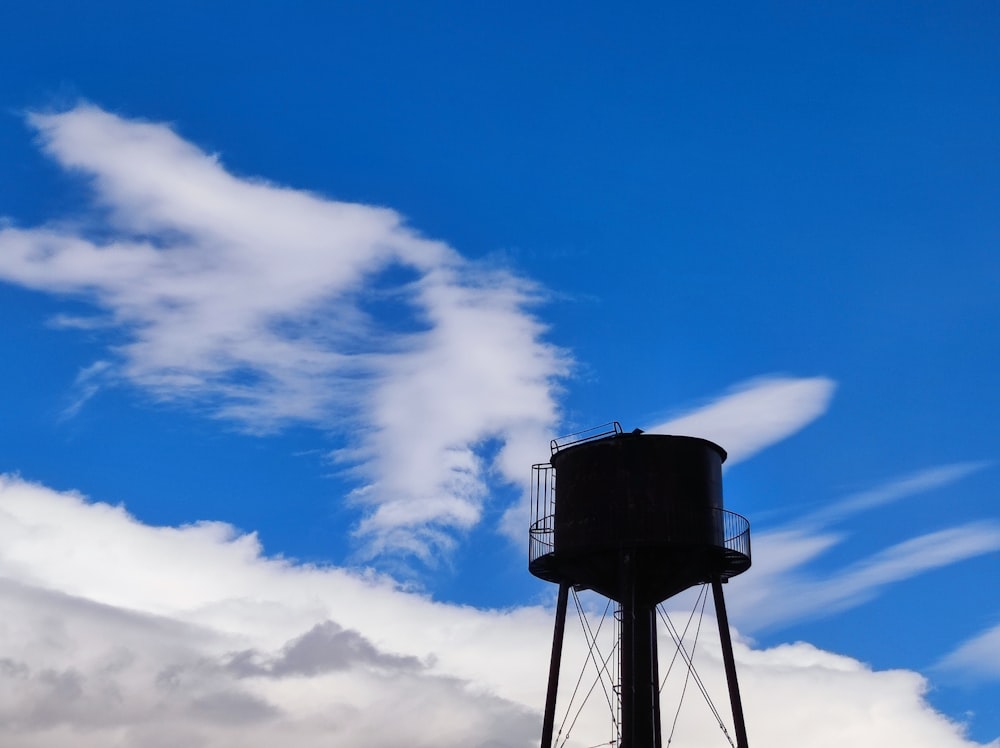 a black water tower with a blue sky in the background