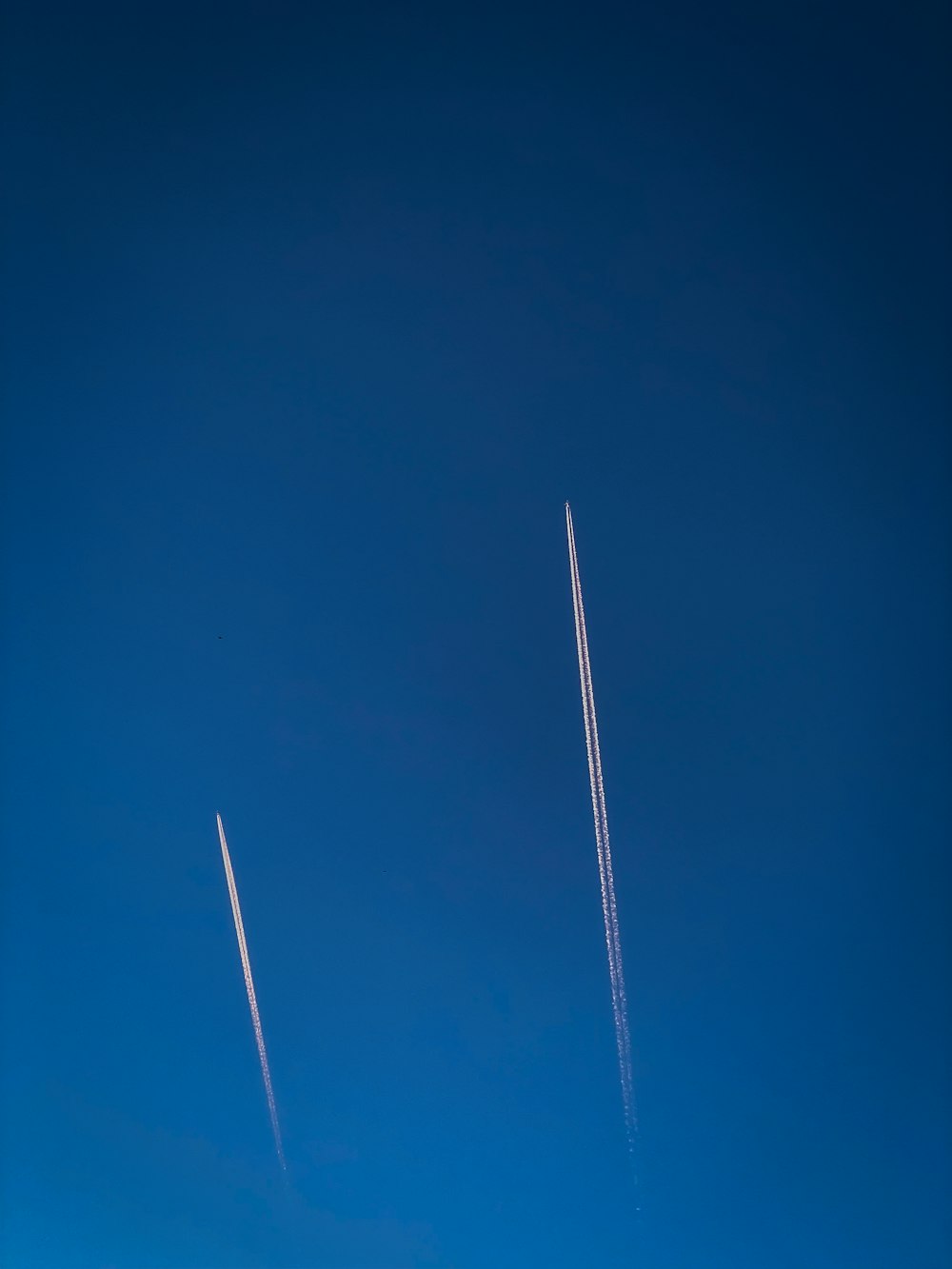 a couple of airplanes flying through a blue sky