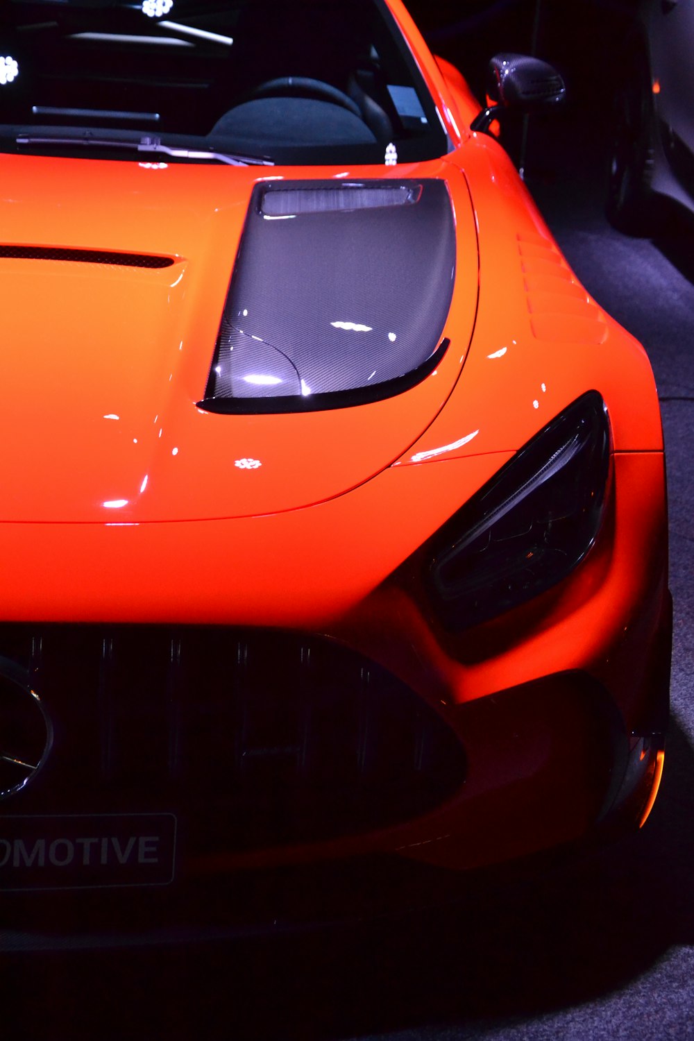 an orange sports car parked in a showroom