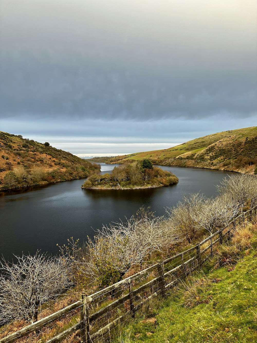 a body of water surrounded by a lush green hillside