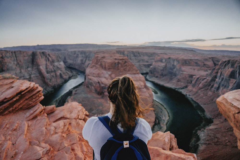 a woman standing on a cliff overlooking a river