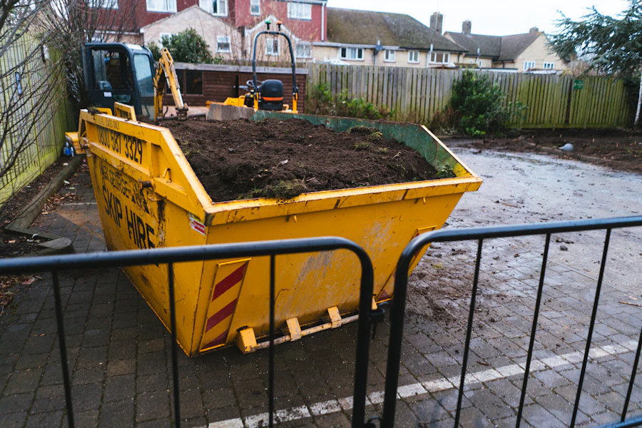 Yellow roll-off container loaded with soil sitting on a paved residential driveway
