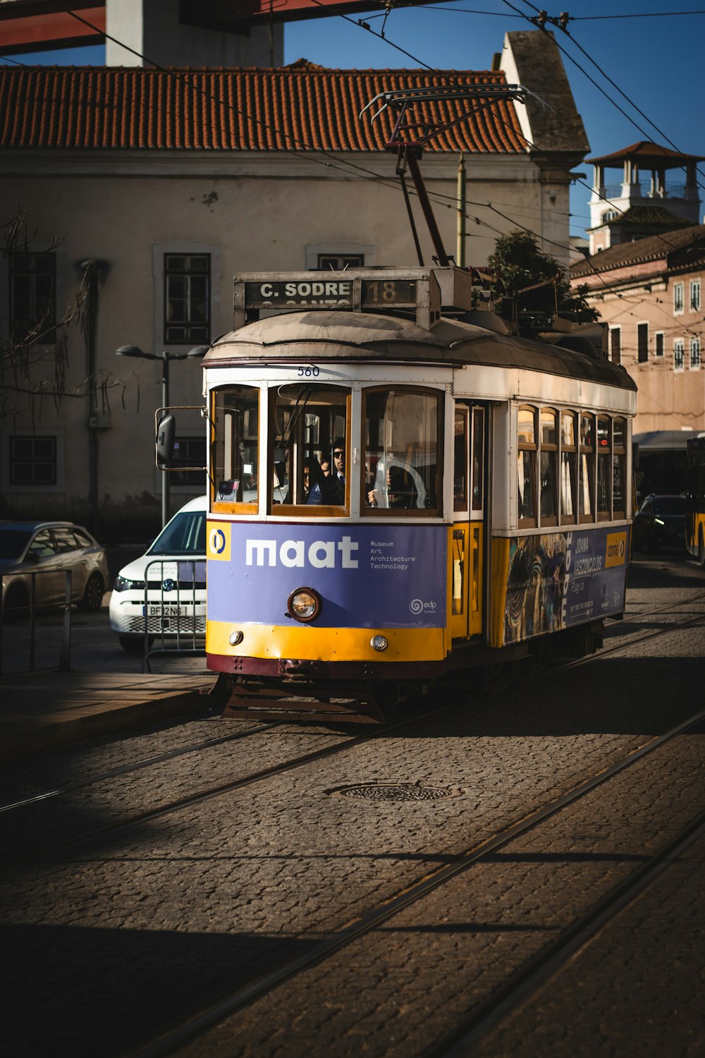 a yellow and blue trolley car traveling down a street