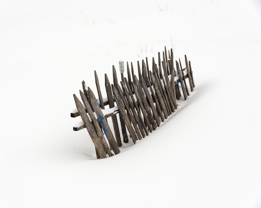 a wooden fence in the middle of a snow covered field