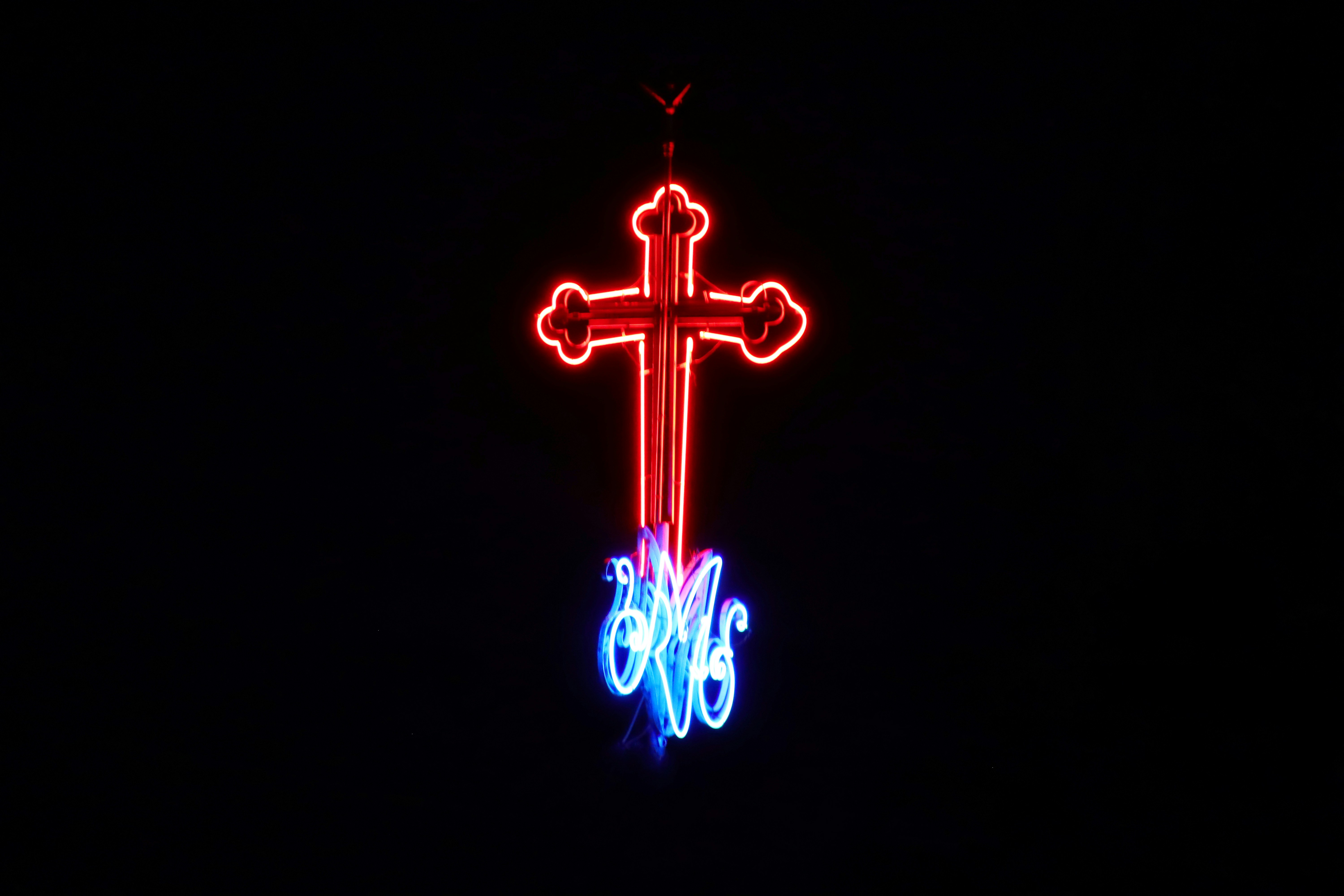 a lighted cross on top of a building in the dark