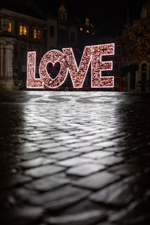 a lighted love sign sitting on top of a sidewalk