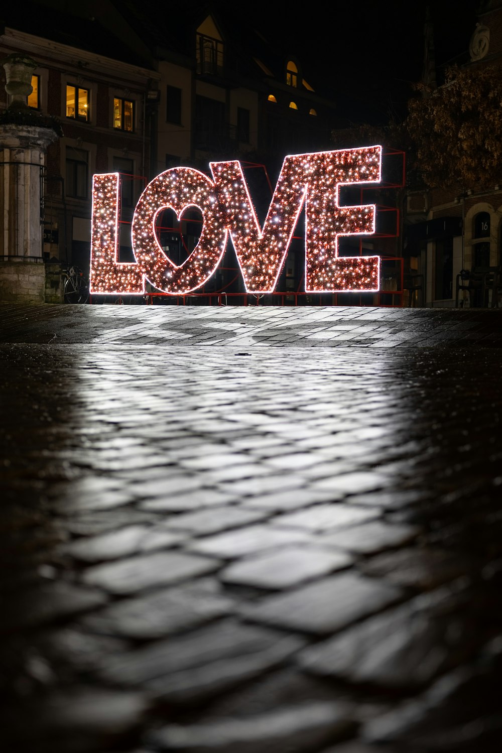 a lighted love sign sitting on top of a sidewalk