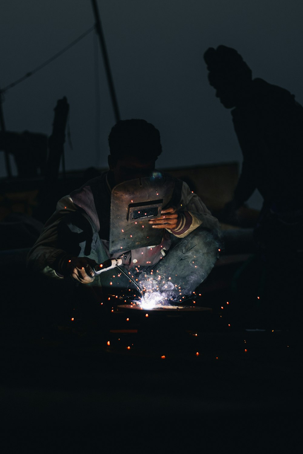 Soldadores trabajando en una pieza de metal en la oscuridad