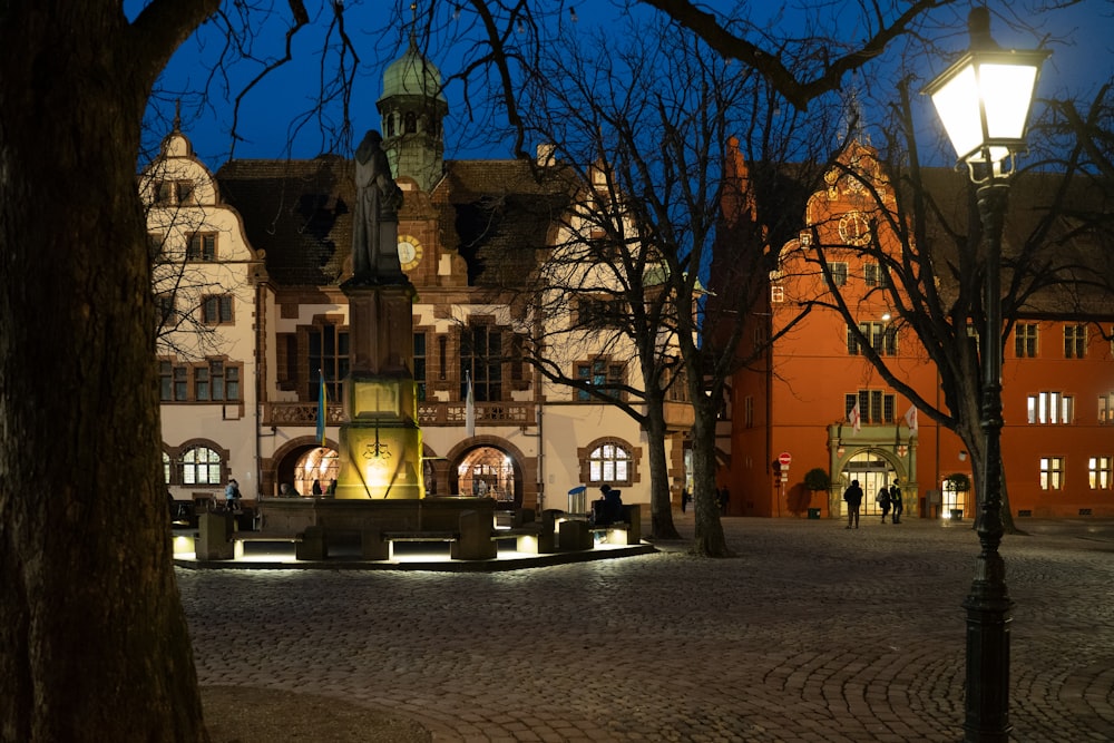 a building lit up at night with people walking around