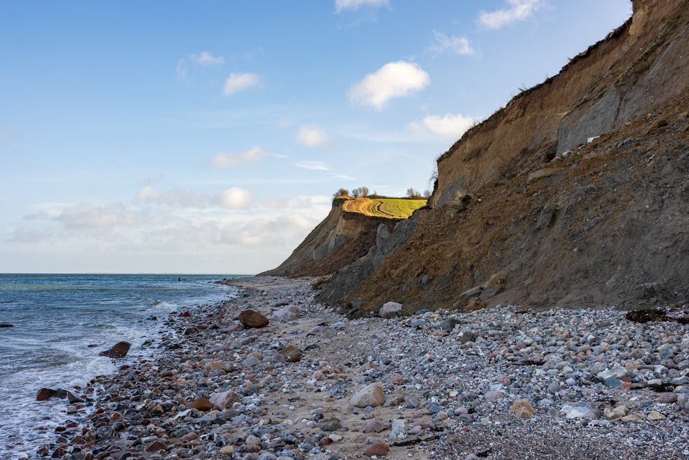 a rocky beach next to a cliff on a sunny day