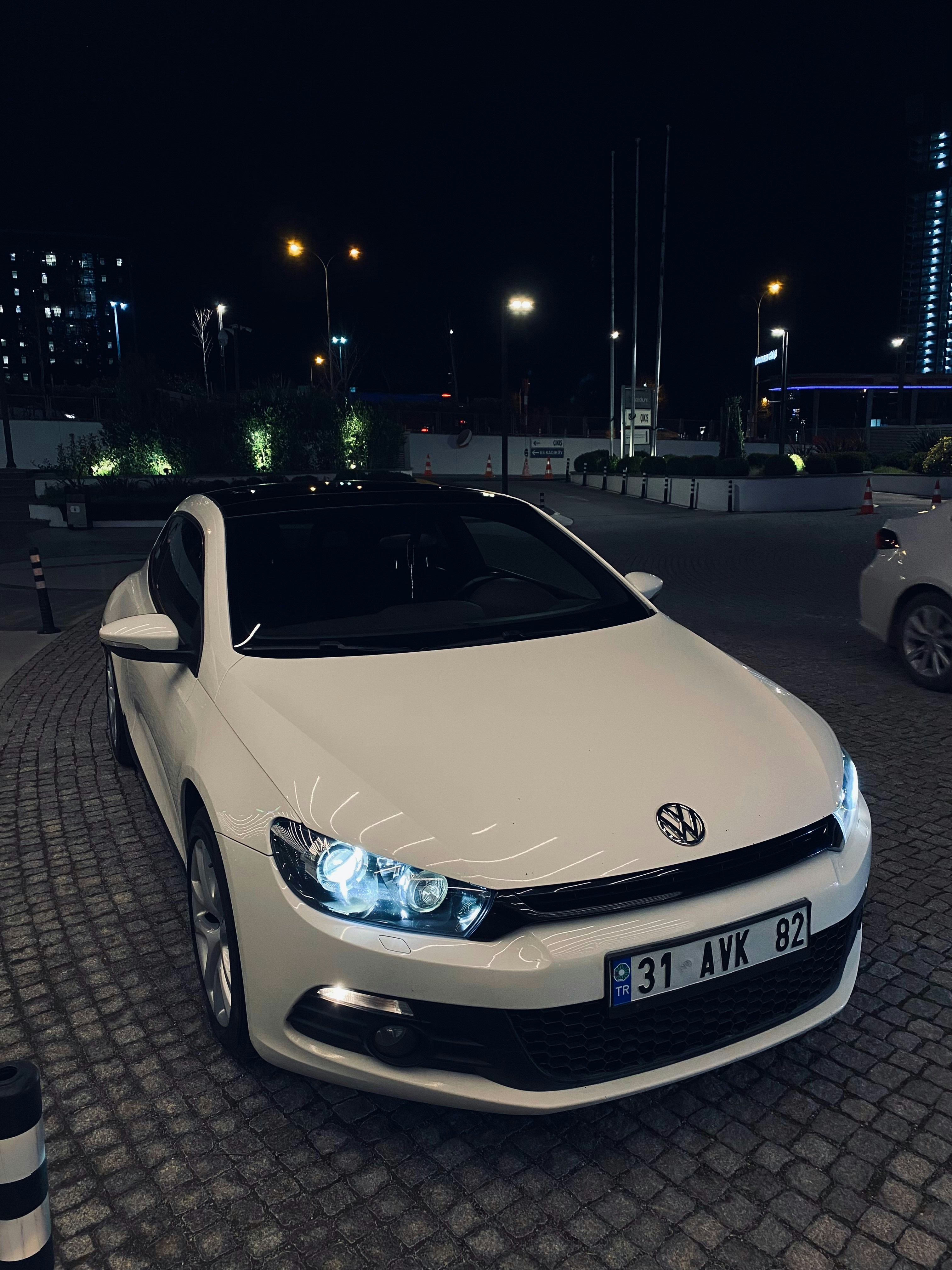 Un coche blanco aparcado en un aparcamiento por la noche