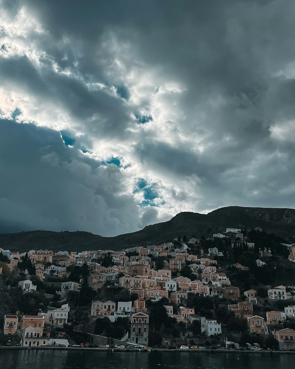 a cloudy sky over a small town on a hill