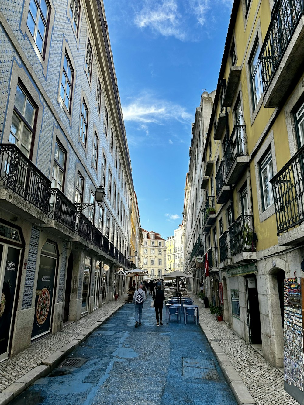 two people walking down a narrow street between two buildings