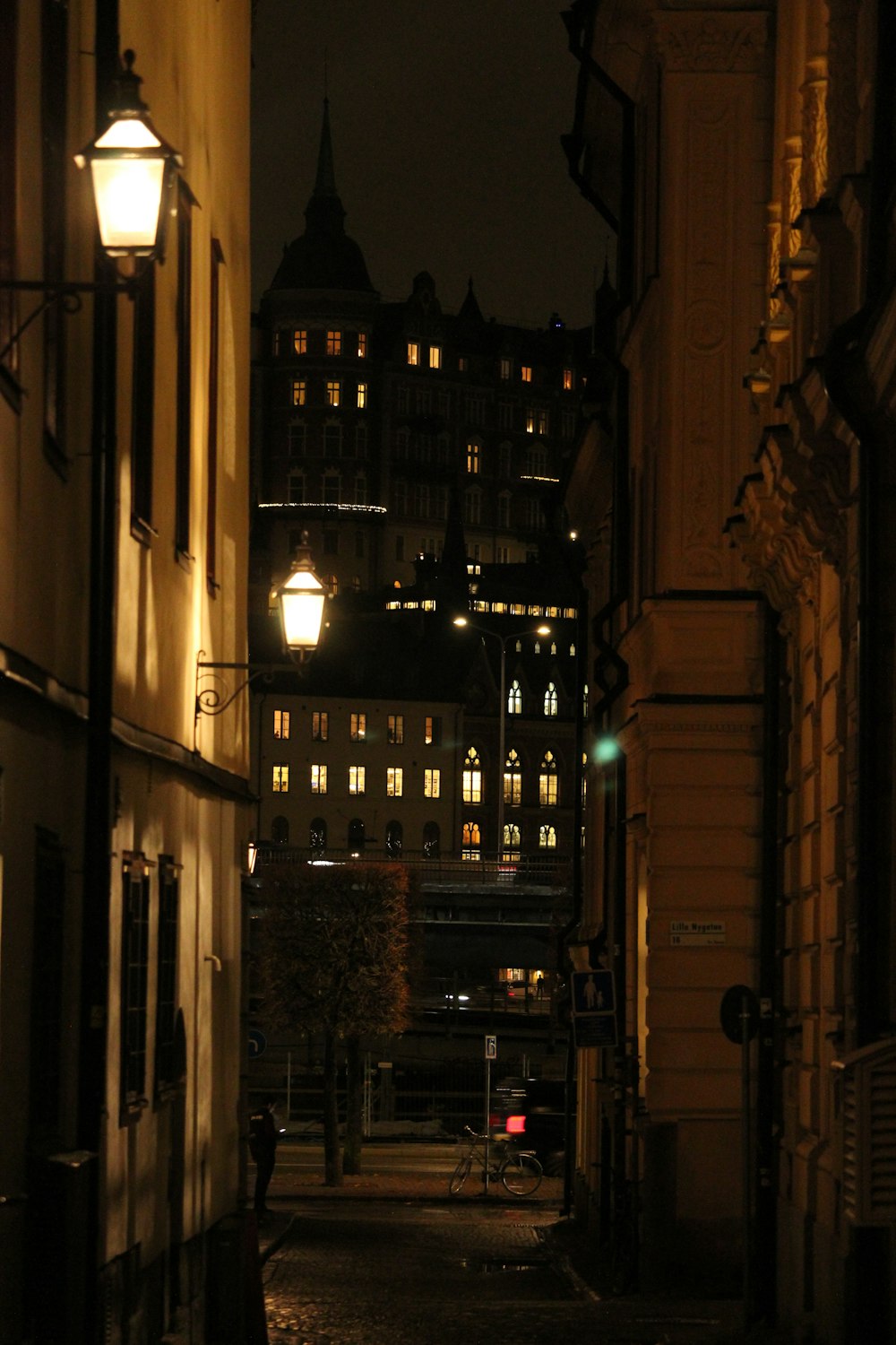 a dark alley way with a street light and buildings in the background