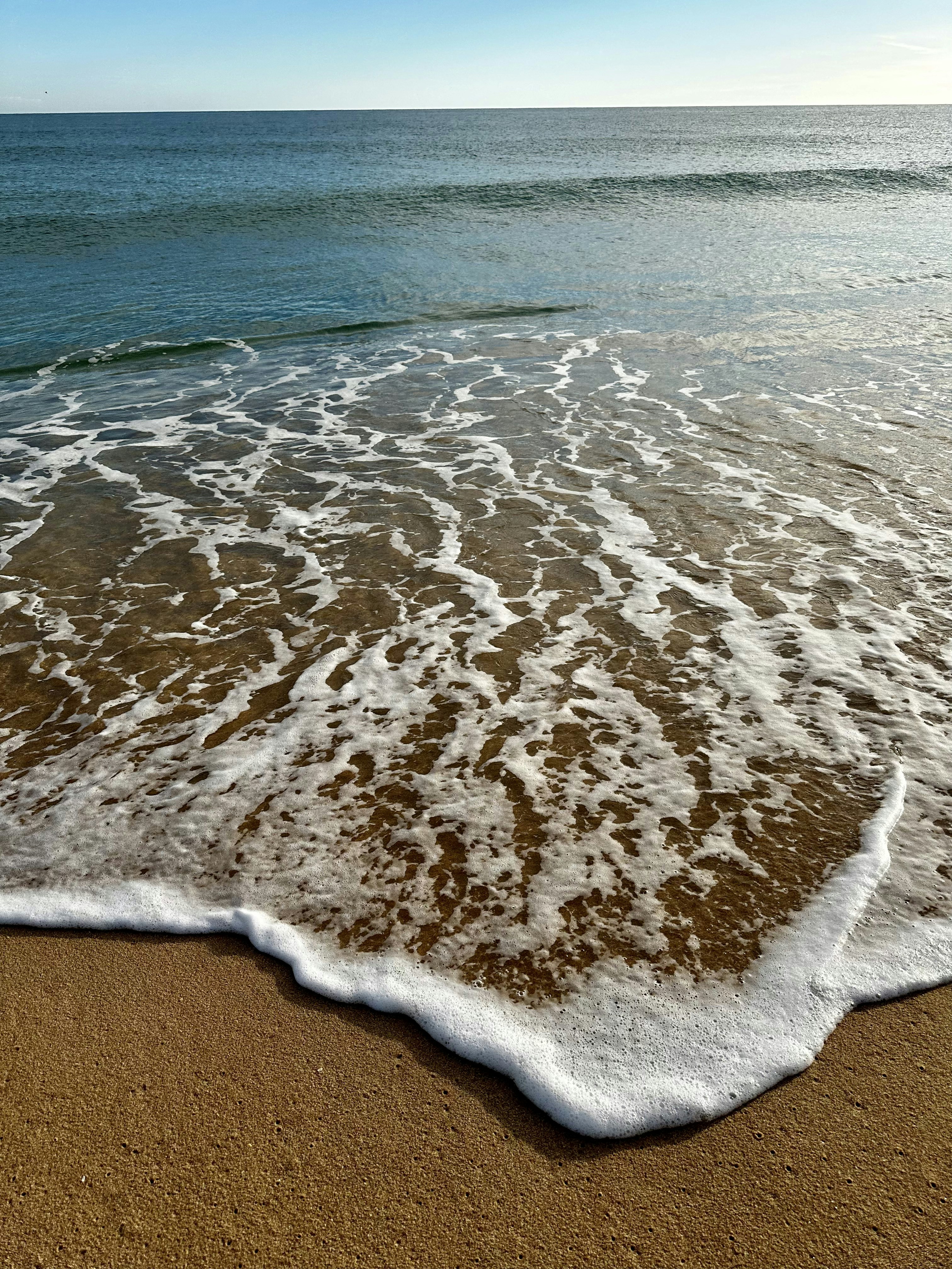 a sandy beach with waves coming in and out of the water