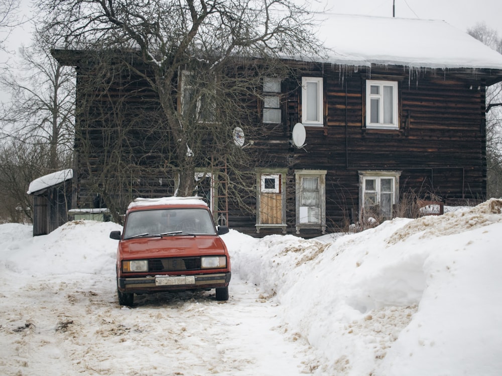 a red truck parked in front of a house covered in snow