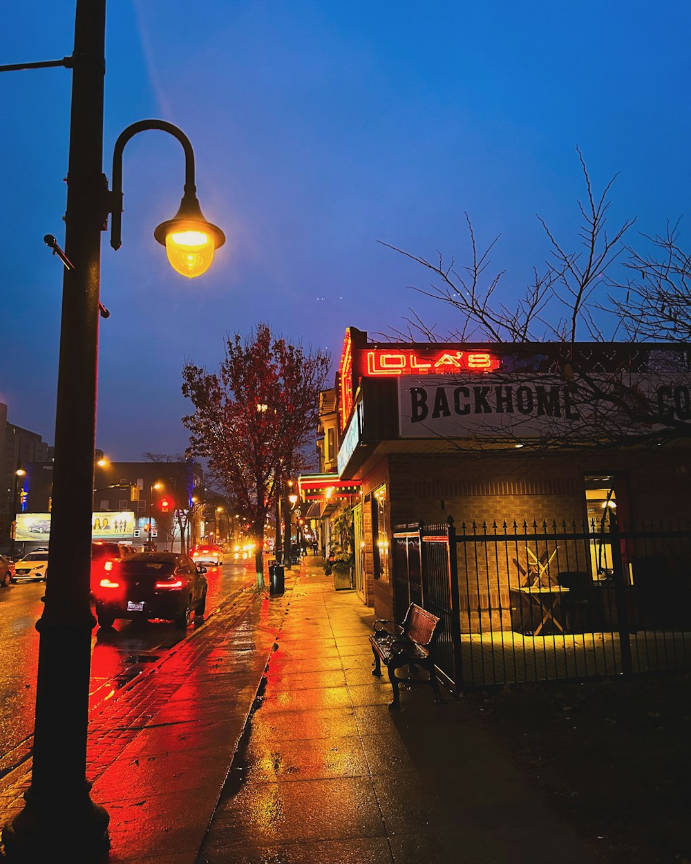 a city street at night with cars parked on the side of the street