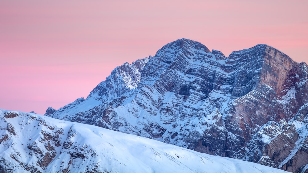 a snowy mountain with a pink sky in the background