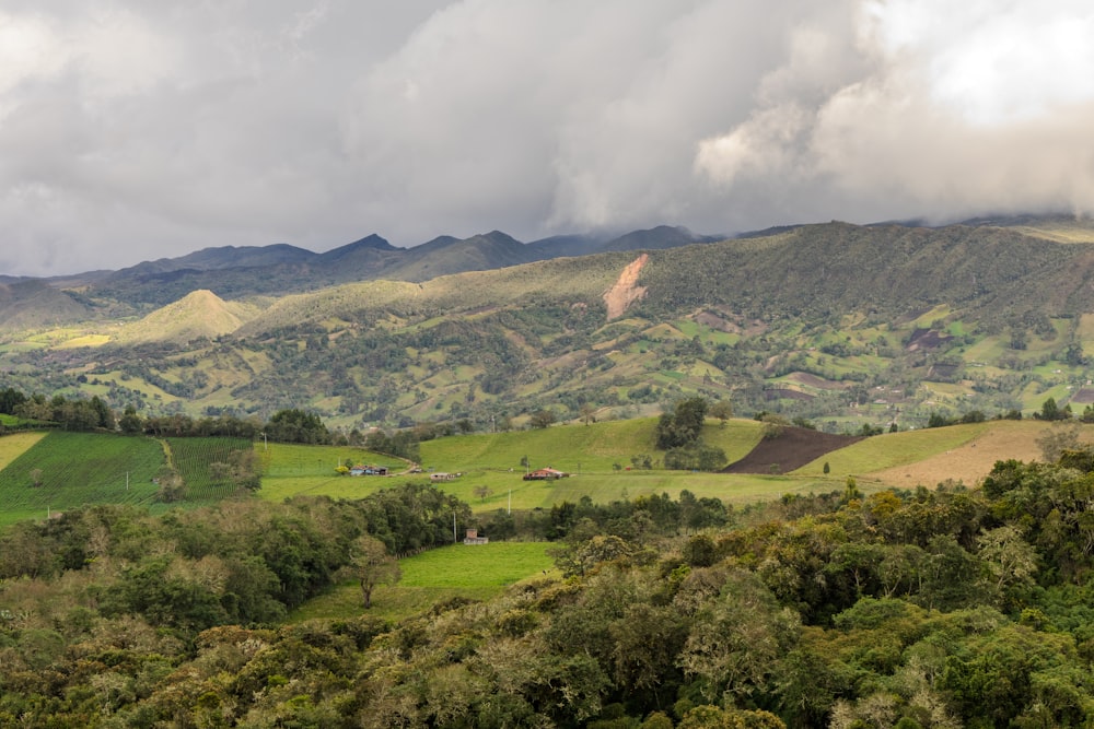 a lush green valley surrounded by mountains under a cloudy sky