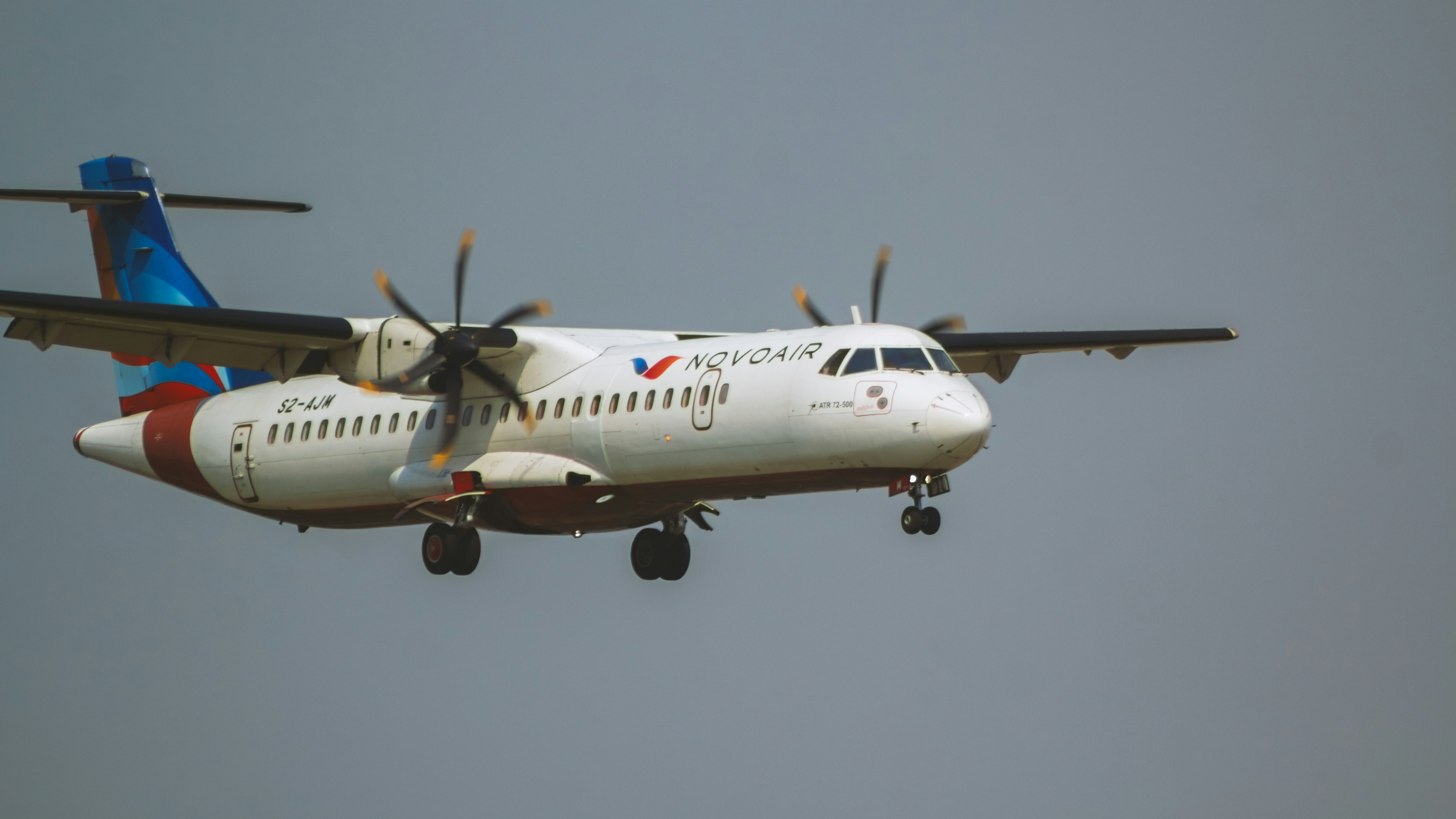 a large passenger jet flying through a gray sky, Novoair ATR 72-500