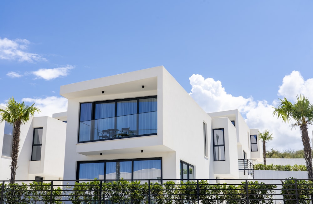 a white house with a black fence and palm trees