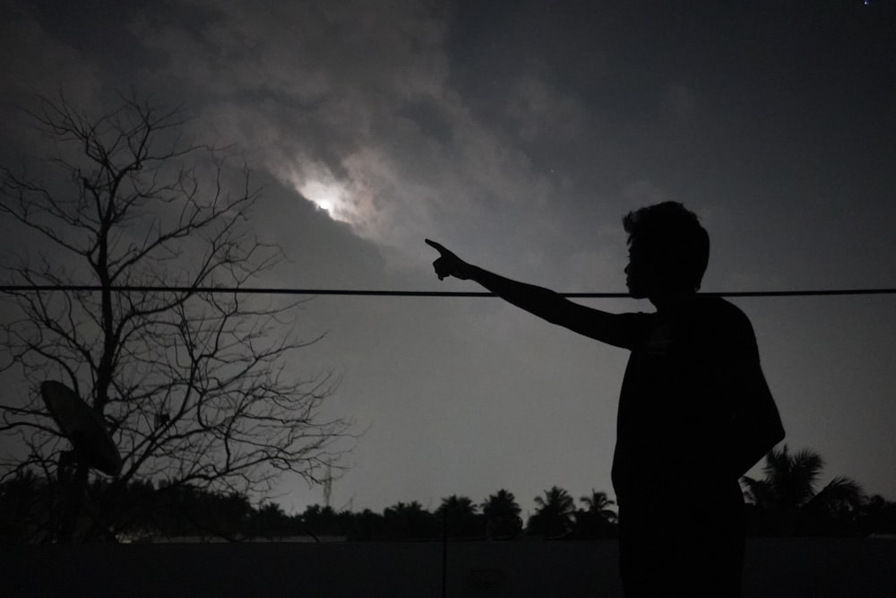 a silhouette of a person pointing at the sky