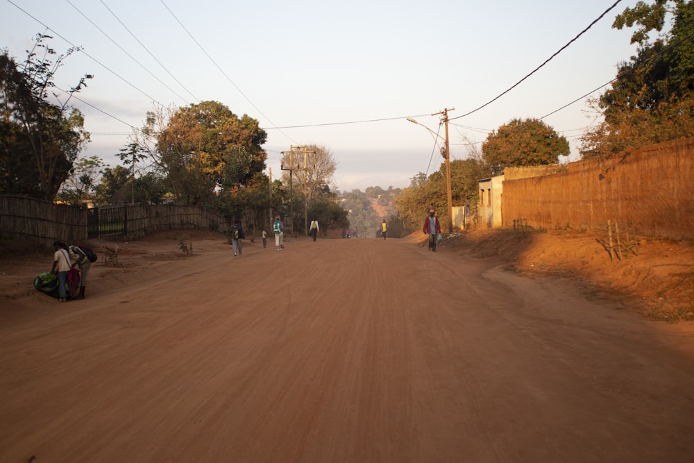 a group of people walking down a dirt road