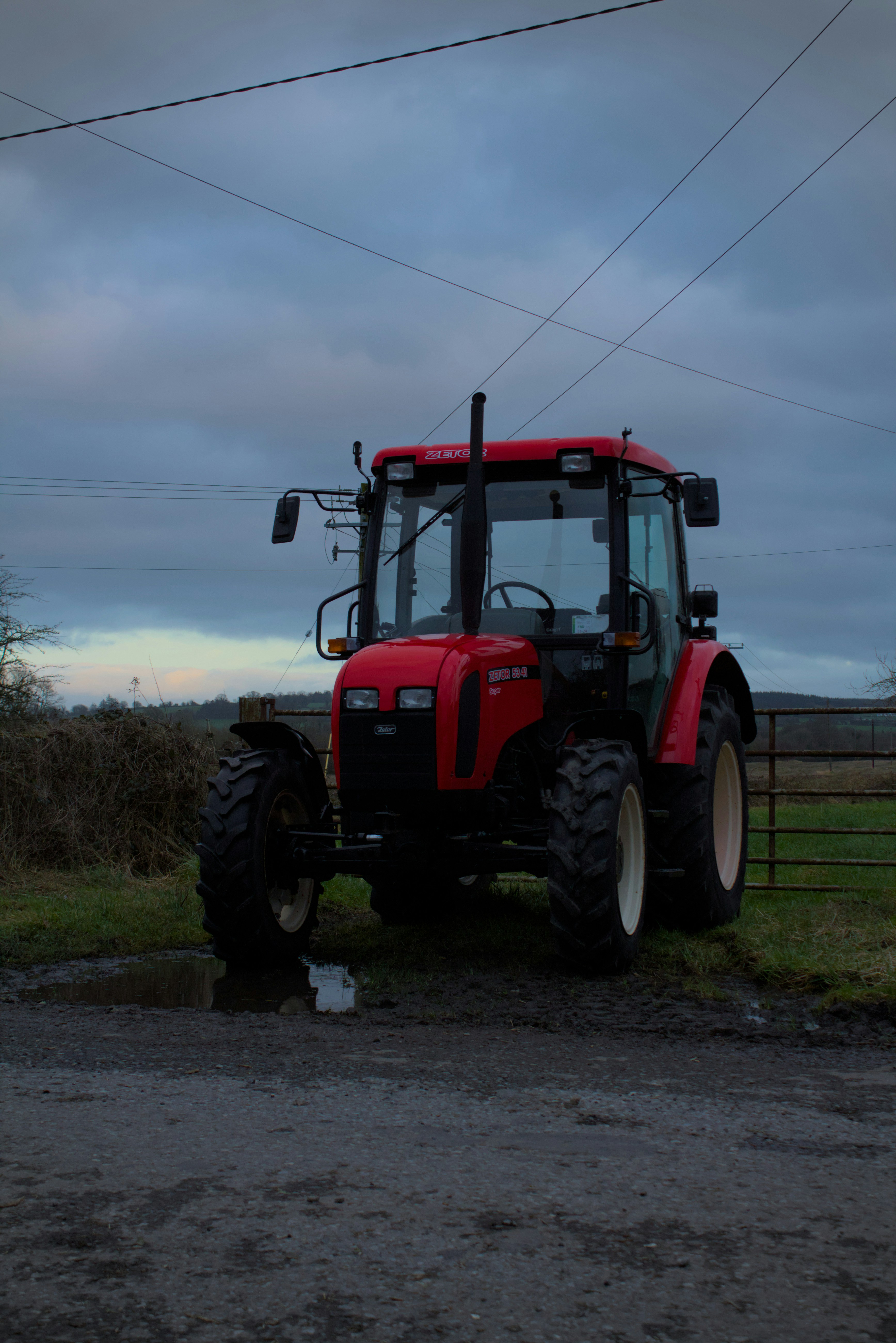 a red tractor parked in a field next to a fence