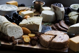 a wooden cutting board topped with lots of different types of cheese