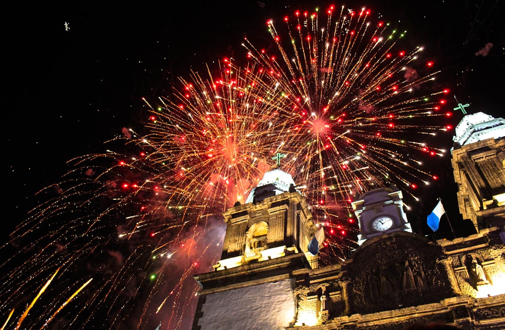 fireworks are lit up in the night sky above a building