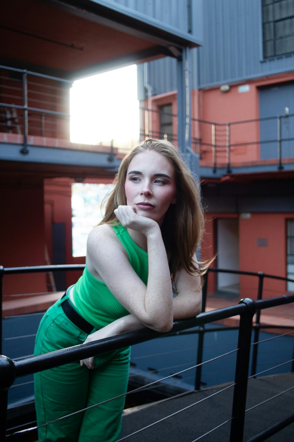 a woman in a green dress leaning on a railing