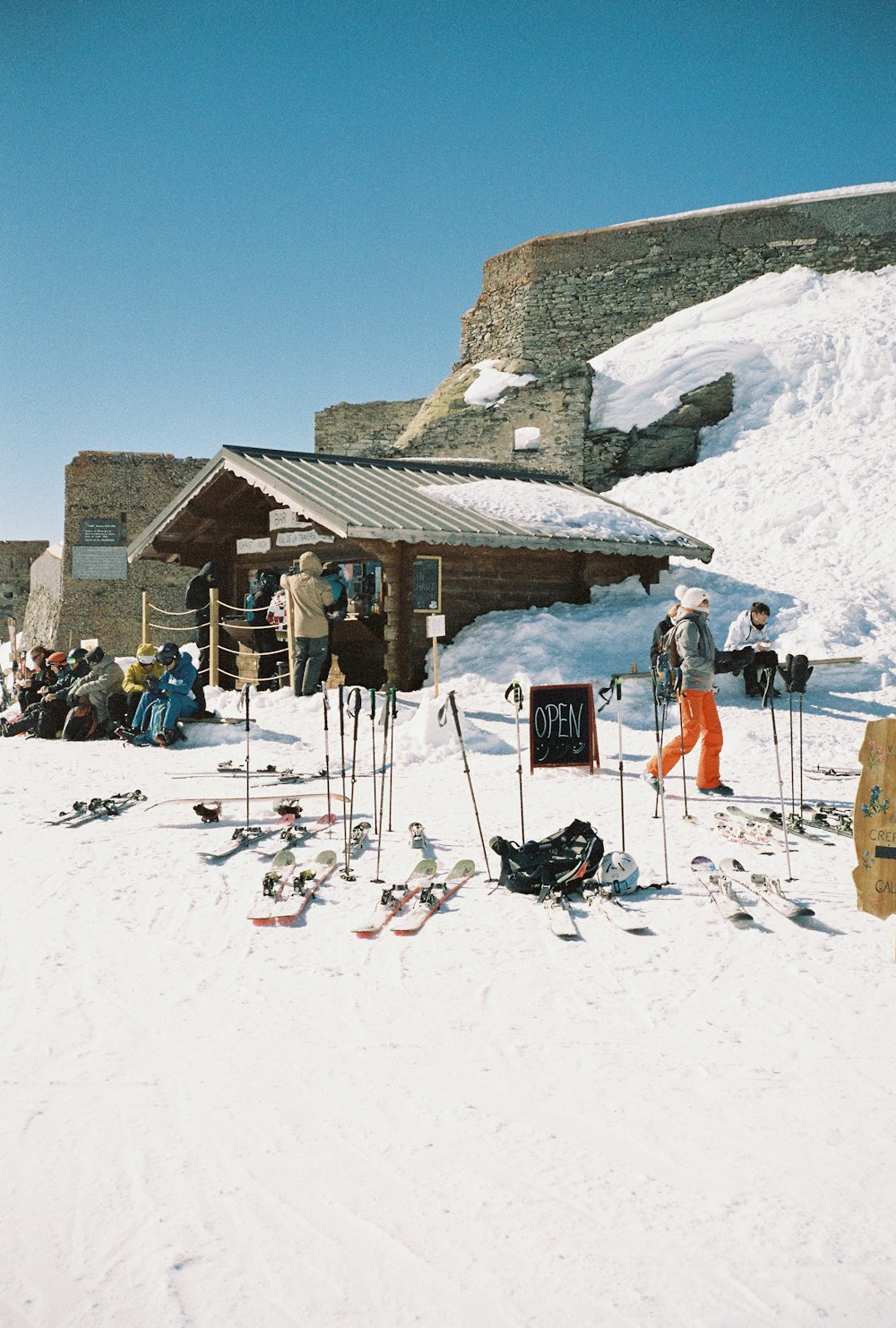 un groupe de personnes debout au sommet d’une pente enneigée