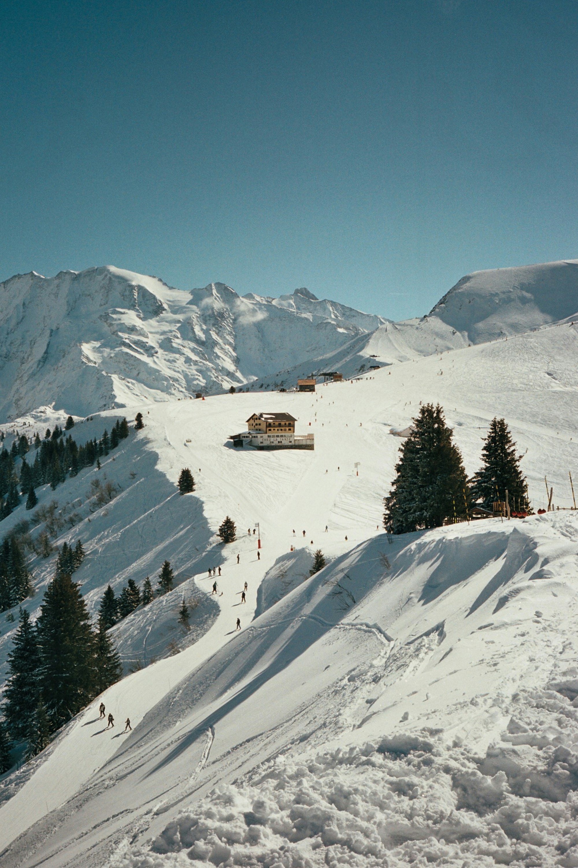 Skiers descending wide groomed pistes at golden hour with mountain village below