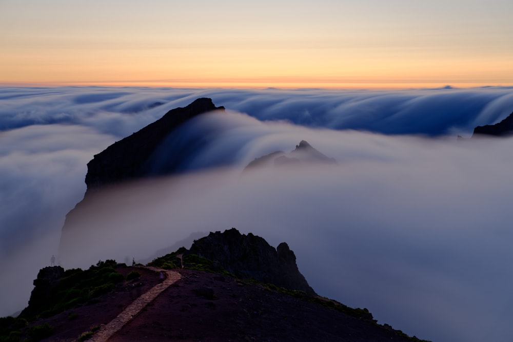 a mountain covered in clouds at sunset