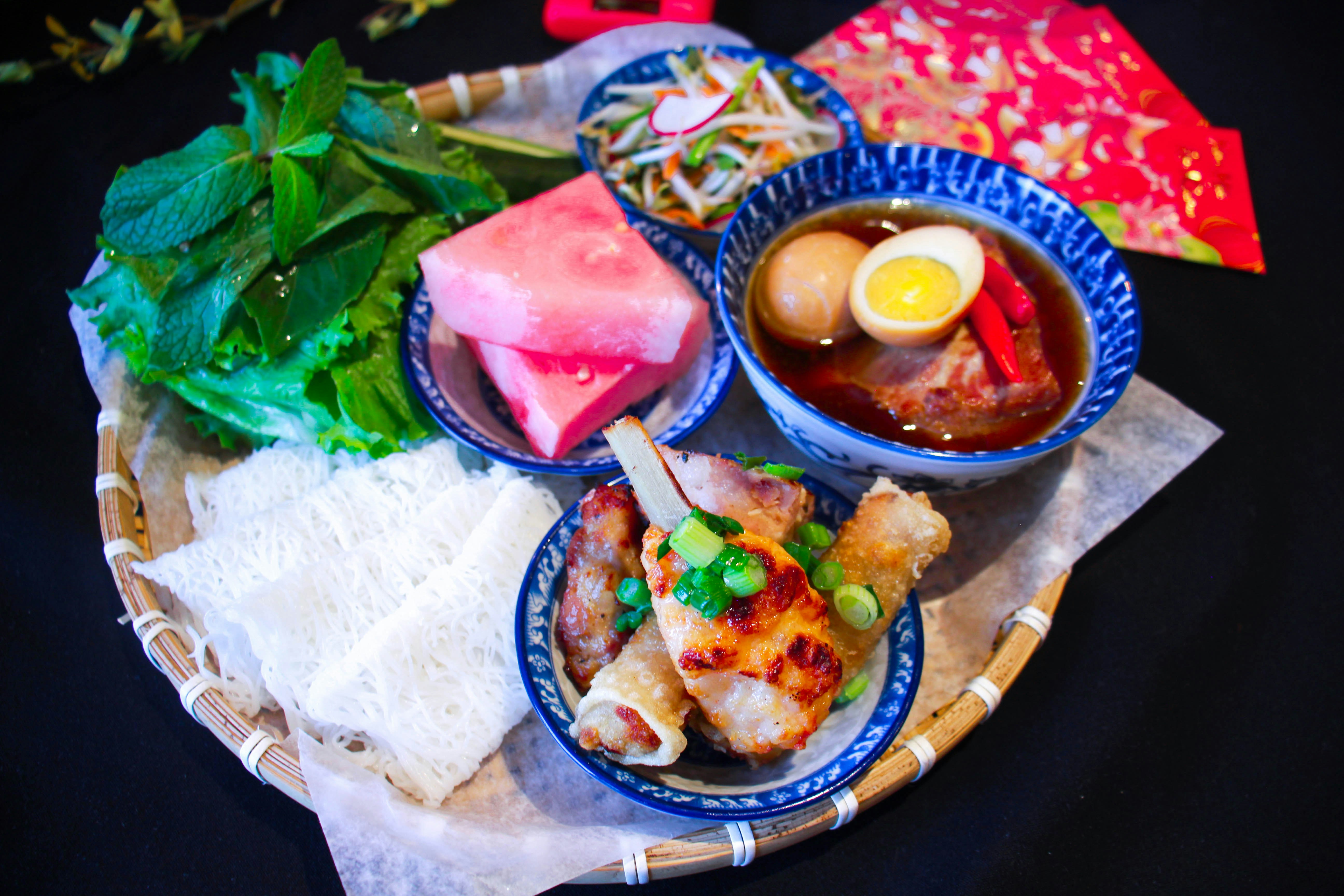 Vietnamese bun cha ram with grilled pork, crispy spring rolls, rice noodles and fresh herbs on a plate