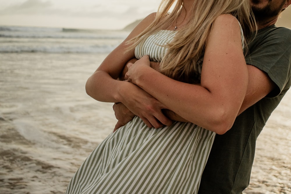 a man and a woman embracing on the beach