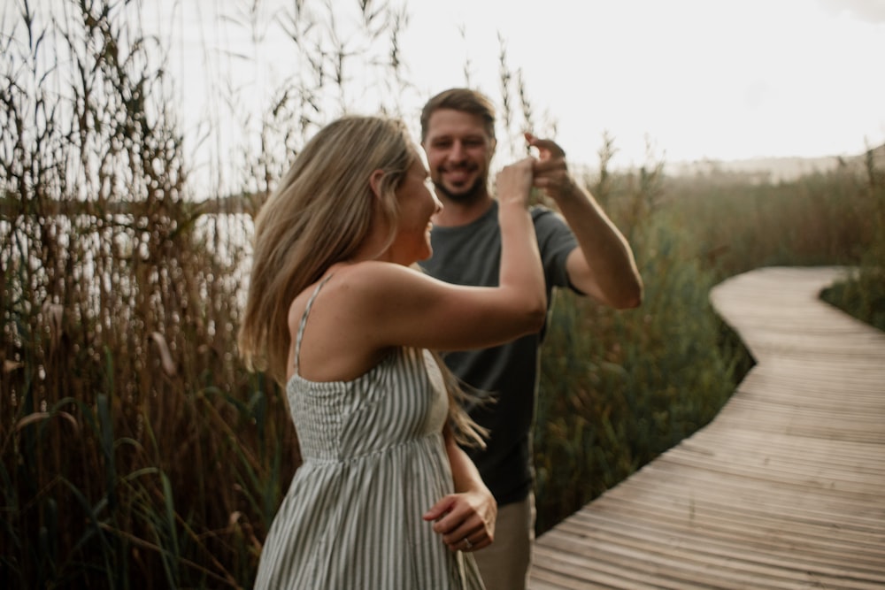 a man taking a picture of a woman on a boardwalk