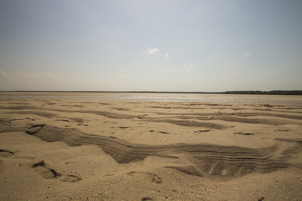 uma praia de areia com um corpo de água ao longe