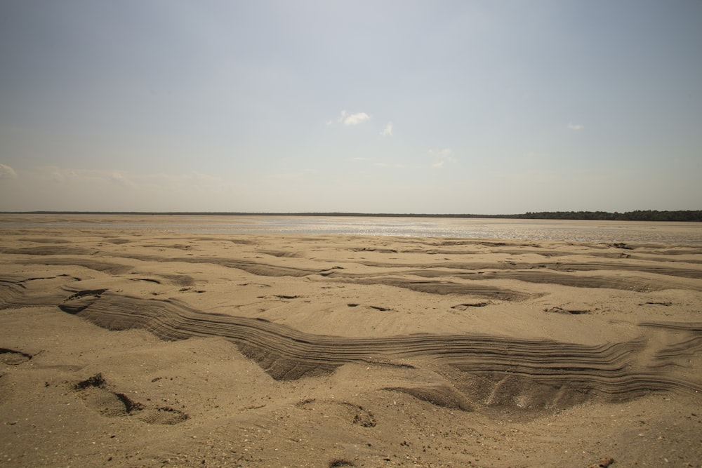 a sandy beach with a body of water in the distance