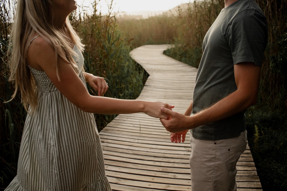 a man and a woman standing on a wooden walkway