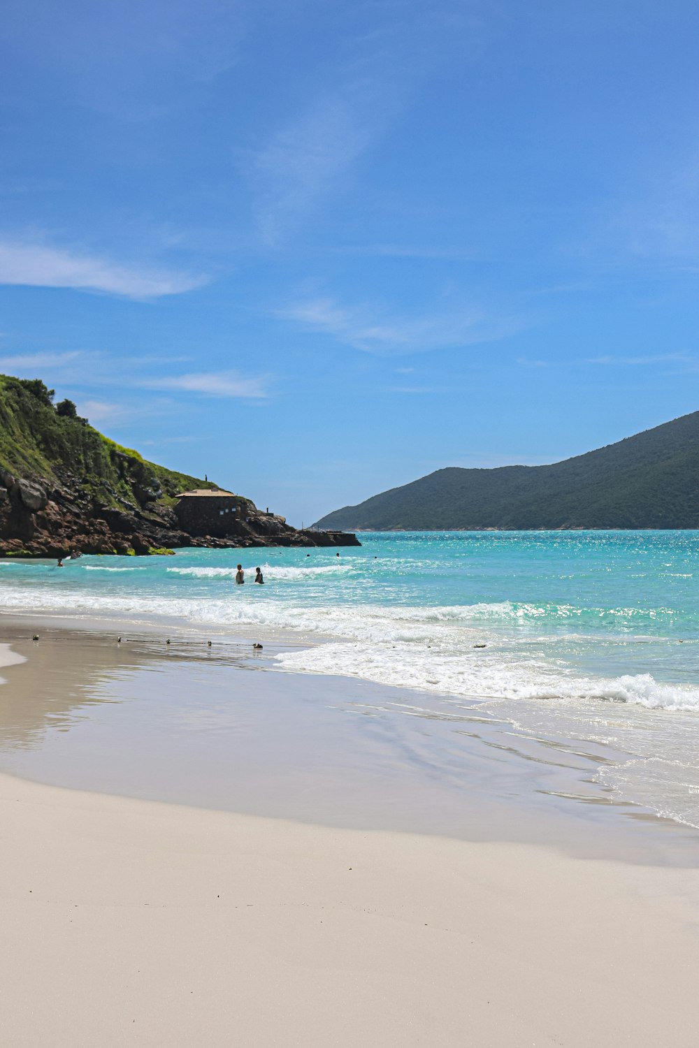 a sandy beach with a hill in the background