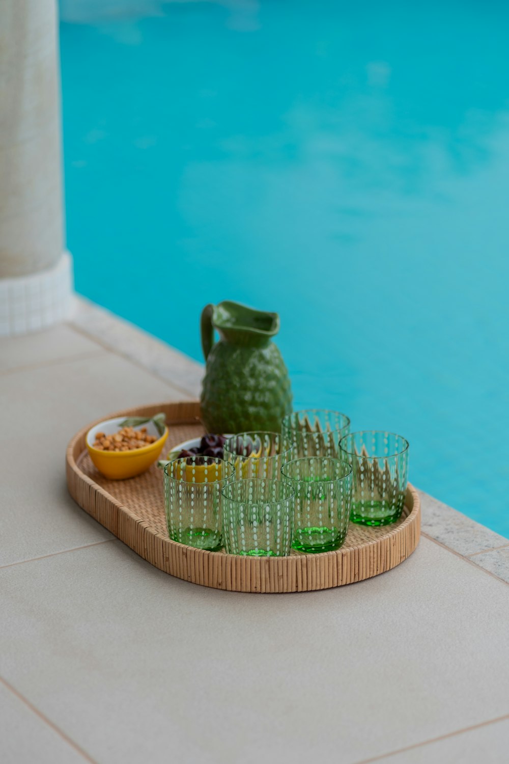 a tray of glasses next to a swimming pool