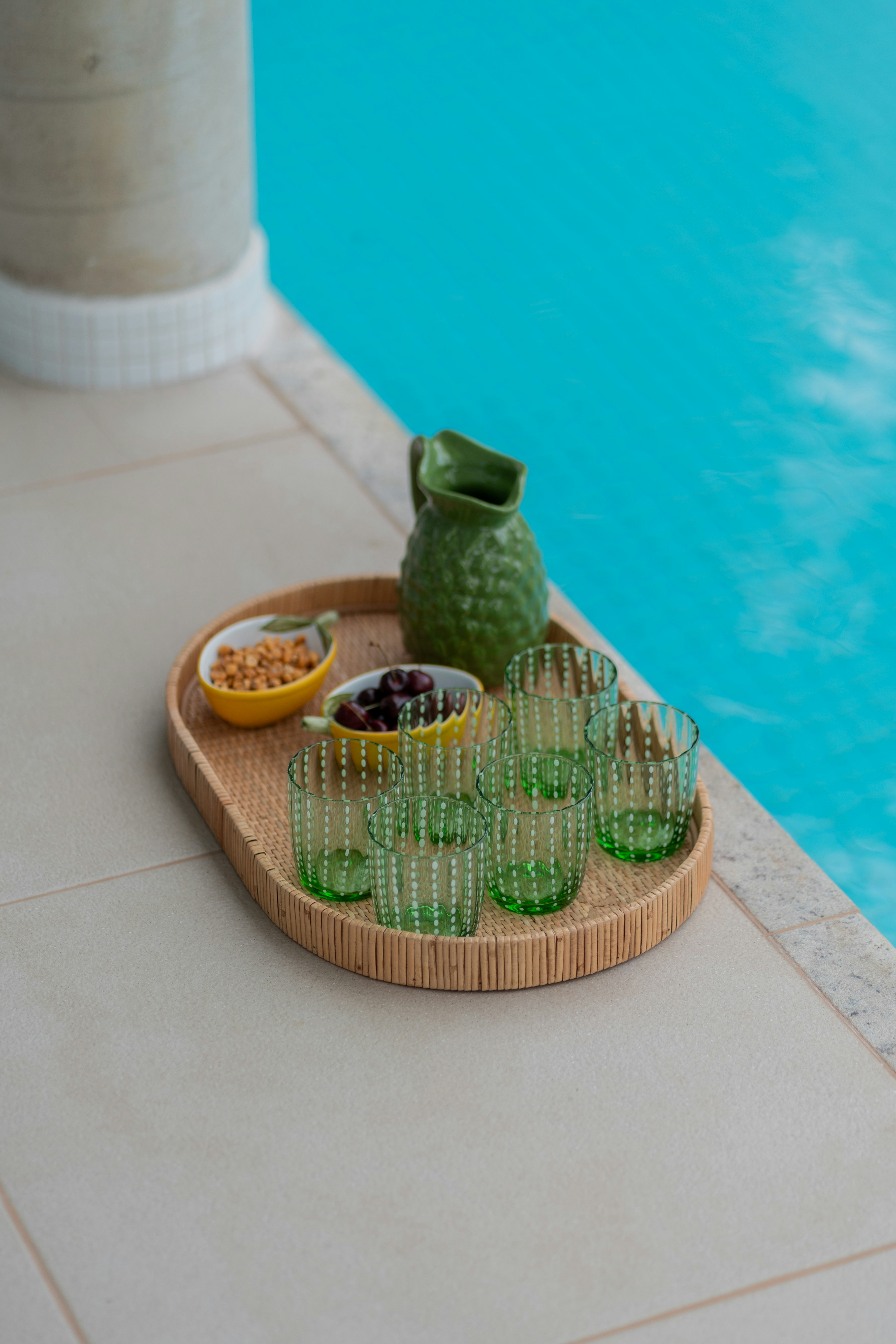 a tray with green glasses next to a swimming pool