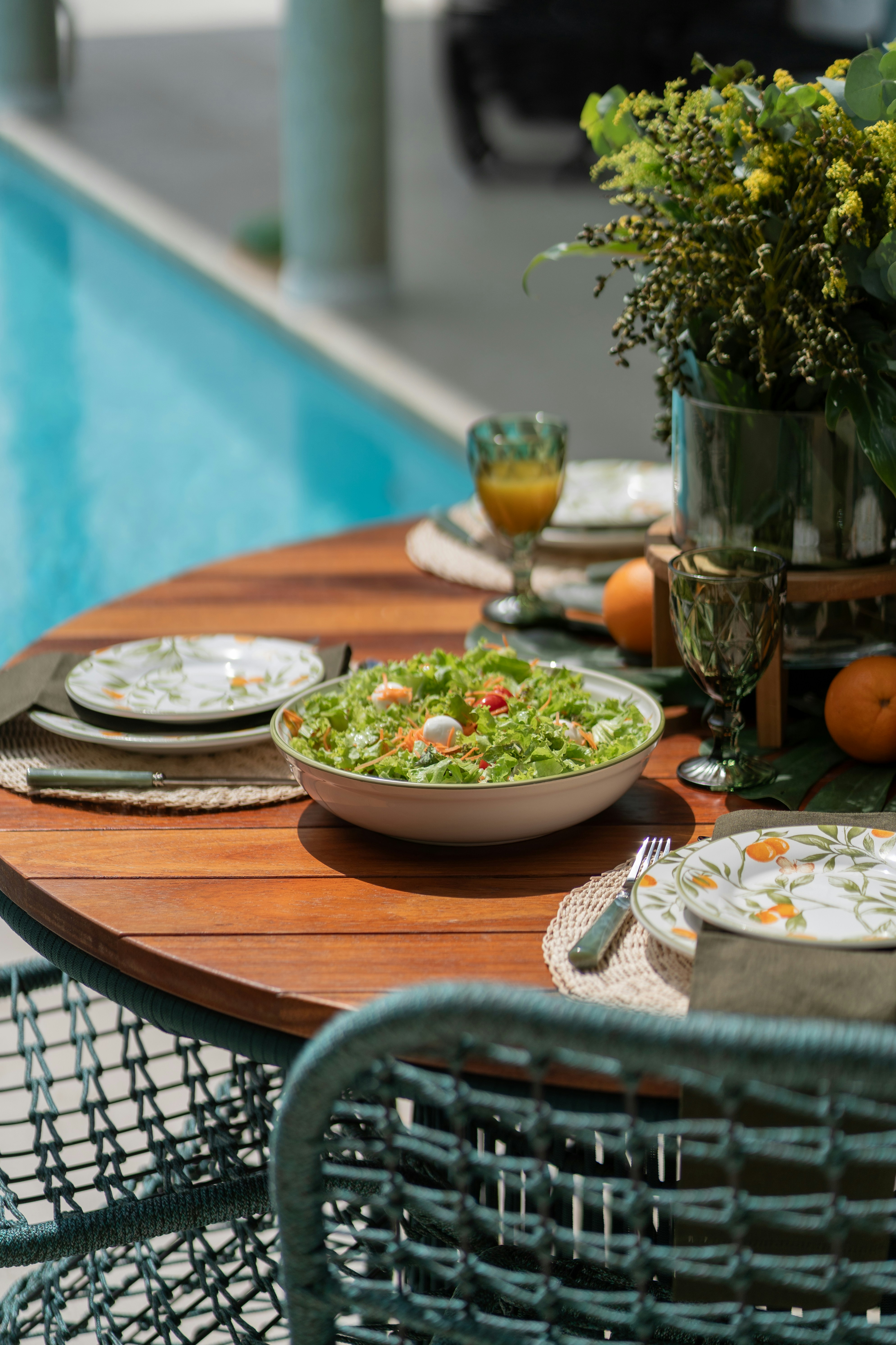 a table with a bowl of salad next to a pool