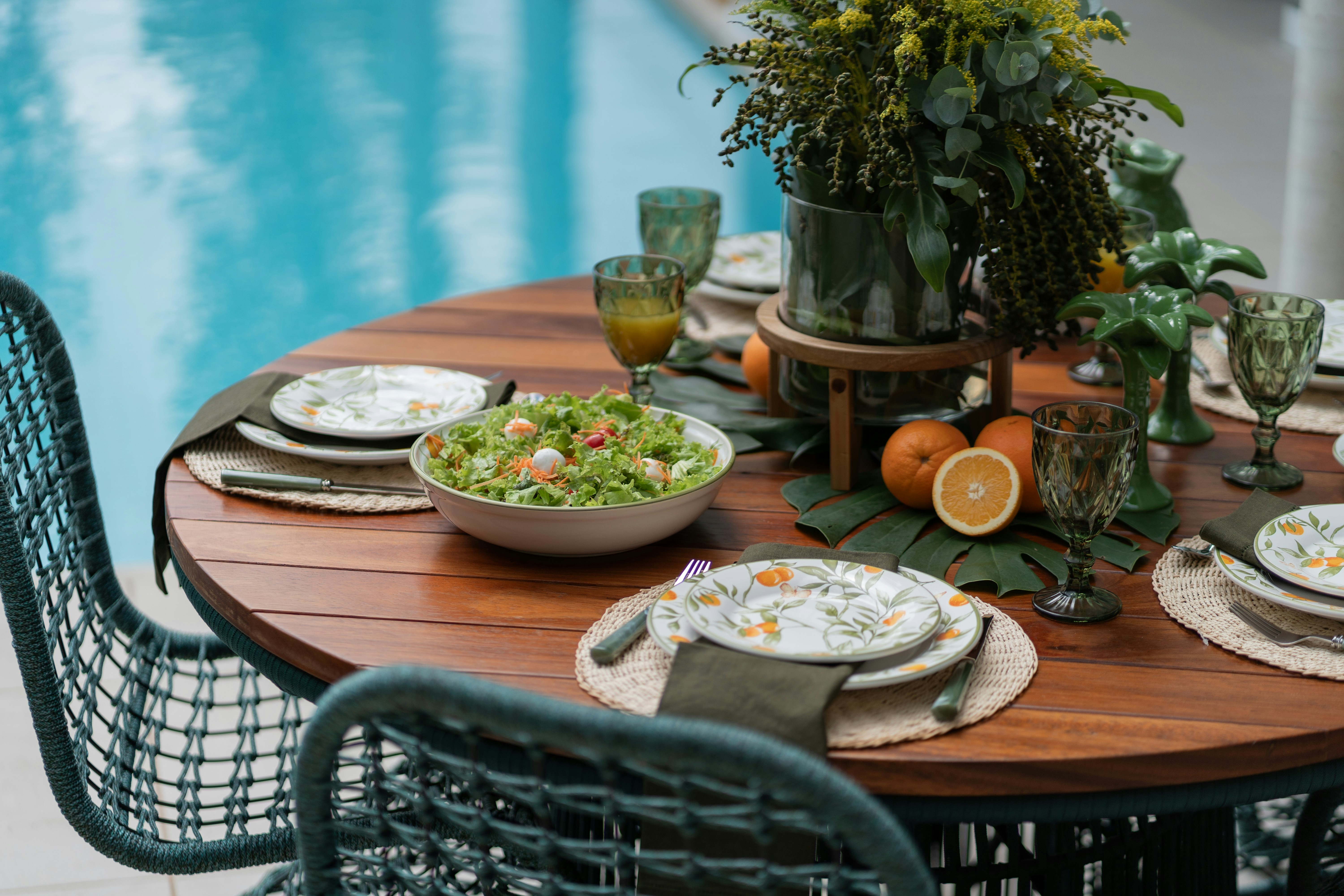 a table with plates and bowls of food near a pool