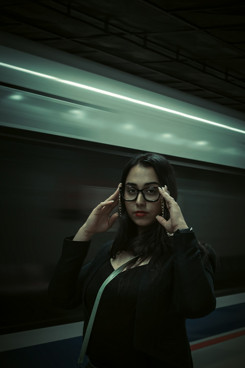 a woman wearing glasses standing in front of a train