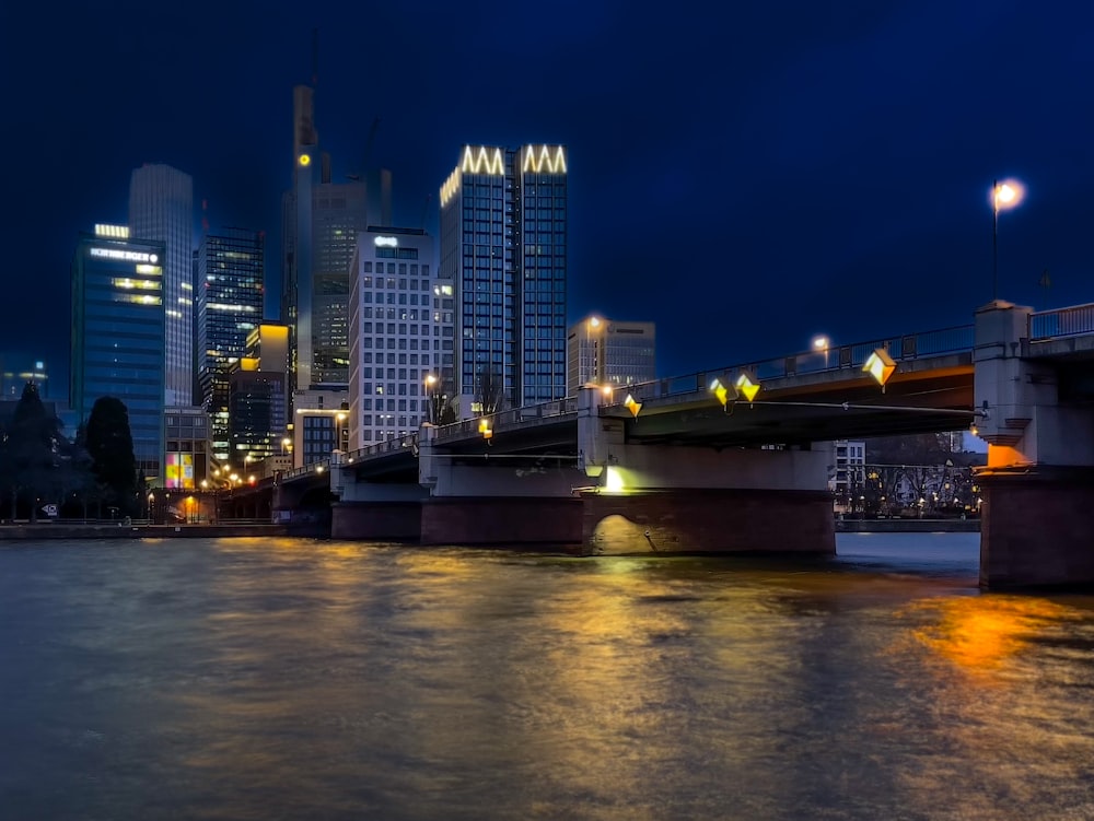 a city skyline at night with a bridge over the water