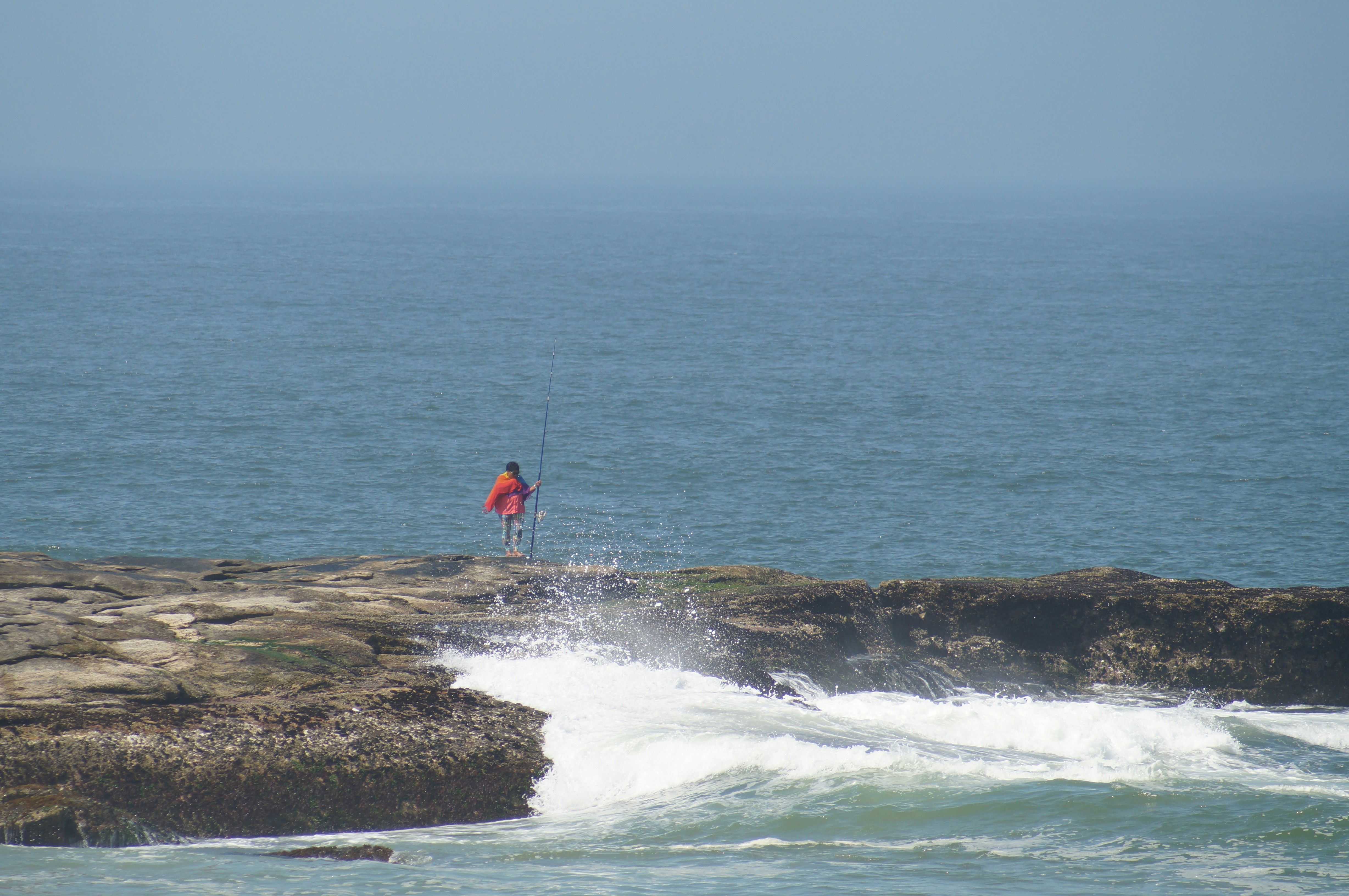 ein Mann, der auf einem Felsen neben dem Meer steht
