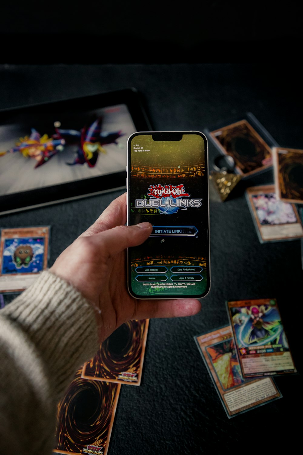 a person holding a cell phone over a table full of cards